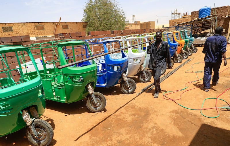 Workers assemble electric tuk-tuks at al-Shehab factory in the Sudanese capital's northern district of Khartoum-Bahri, on April 19, 2022.  - In Sudan, three-wheeler vehicles -- tuk-tuk rickshaws for passengers, and motorbike tricycles with a trailer attached for carrying goods -- have long been a popular and affordable transport.  But with the country gripped by a dire economic crisis made worse by political unrest following a military coup last October, the cost of running petrol-oil engines has soared.  (Photo by ASHRAF SHAZLY  /  AFP)