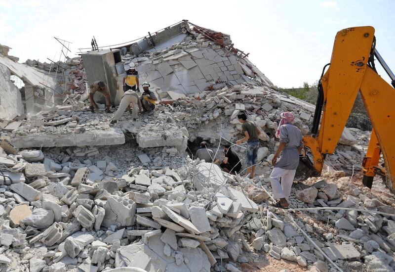 Members of the Syrian Civil Defence (White Helmets) search for victims amid the rubble of a building that collapsed during reported air strikes by pro-regime forces in the village of Beinin, north of Maaret al-Numan, in the northern Idlib province.  AFP