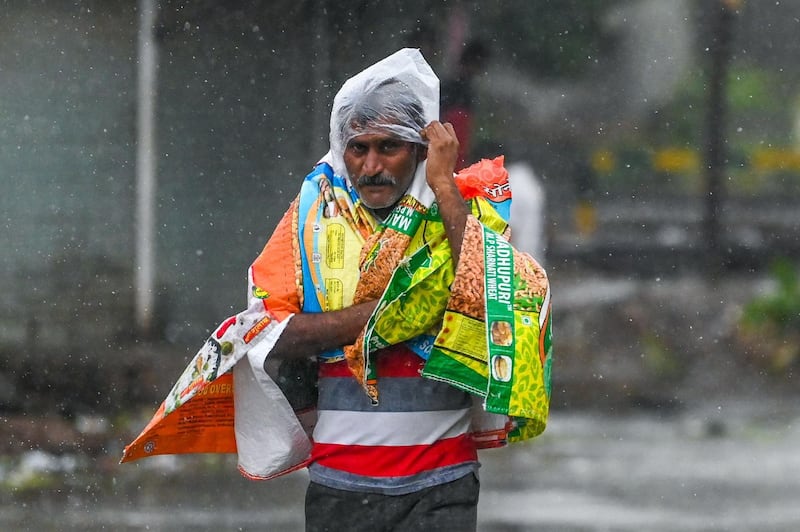 A pedestrian improvises rainwear with plastic bags and scraps in the city of Amreli, Gujurat state, western India. AFP