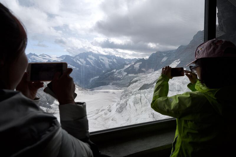 Chinese tourists use their mobile phone to picture the Ischmeer glacier form a window at the Eismeer railway station, 3159 meters high, during their trip at the Jungfraujoch high in the Swiss Alps. Fabrice Coffrini/AFP