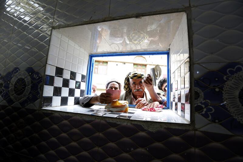 Conflict-affected men wait to get free bread provided by a local charity bakery during the holy fasting month of Ramadan in Sanaa, Yemen.   EPA