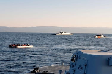 A dinghy full of migrants, with Turkish ships in the background. Hellenic Coastguard via AP