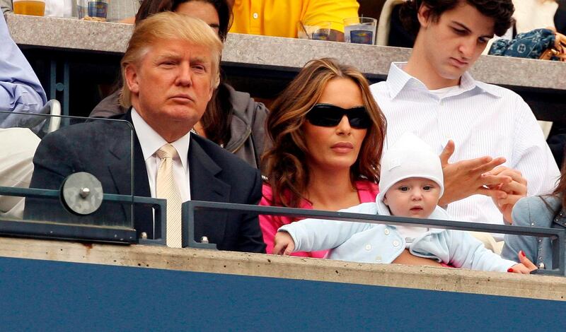 epa00814832 Donald Trump sits with his wife Melania (R) as she holds their son Barron William Trump as they watch Andy Roddick of the US play Roger Federer of Switzerland during the men's final on the final day of the 2006 US Open tennis tournament in Flushing Meadows, New York Sunday 10 September 2006.  EPA/JASON SZENES