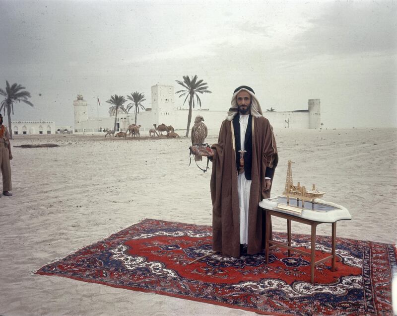 Emirati Sheik Shakbut bin Sultan Al Nahyan (circa 1905 - 1989), a falcon on his arm, stands on a carpet in the sand in front of his palace, 1963. On a table beside him is a model of an oil rig. (Photo by Ralph Crane/Time & Life Pictures/Getty Images)