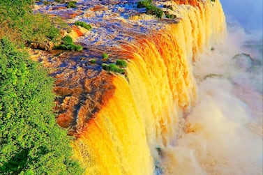 Impressive Iguacu falls at dramatic gold colored sunset, one of the most beautiful waterfalls in the world and one of the seven Wonders of Nature, dramatic beauty in nature landscape - Idyllic Devil's Throat - international border of Brazilian Foz do Iguacu city, Parana State, Argentina Puerto Iguazu city, Misiones province and Paraguay - rainforest landscape panorama, South America. Getty Images