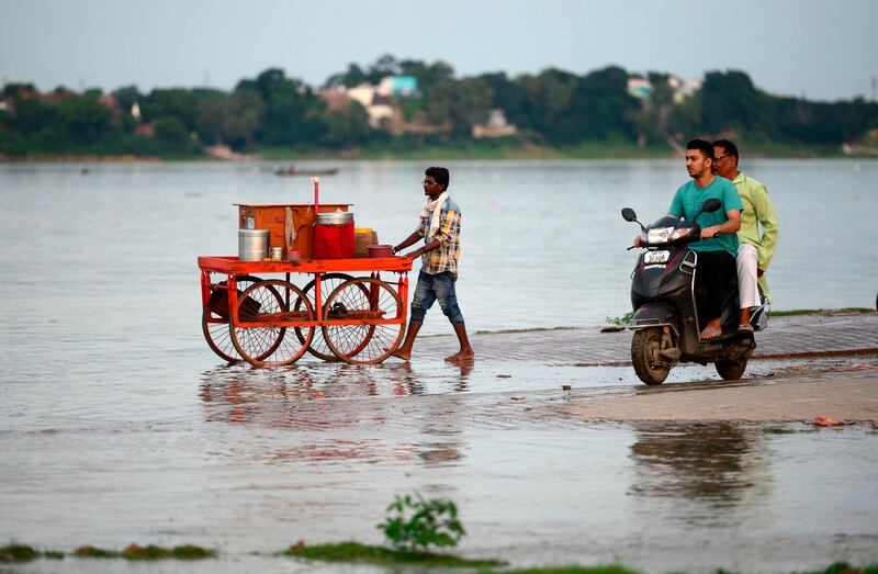 A street vendor pushes his cart while residents ride near a flooded area near the Sangam, the confluence of the Ganges, Yamuna and mythical Saraswati rivers, as the water level of the Ganges and Yamuna rivers rises rapidly during monsoon rains in the region, in Allahabad. AFP