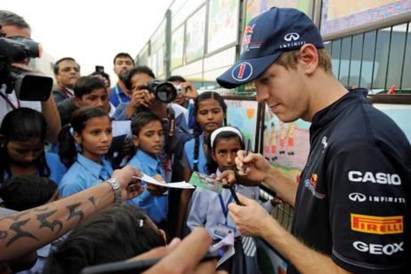 epa02982041 German Formula One driver Sebastian Vettel (R) of Red Bull Racing signs autographs to local school children at the Buddh International Circuit on the outskirts of New Delhi, India, 27 October 2011. India is to host its first Formula One Grand Prix on 30 October 2011.  EPA/FRANCK ROBICHON *** Local Caption ***  02982041.jpg