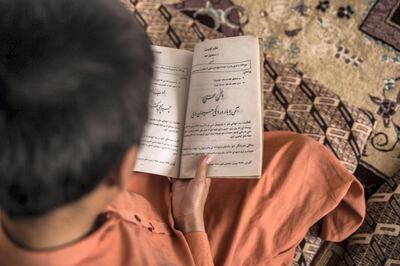 Adeel, 11, reads one of his school books at home in his living room. He's originally from Pakistan, but lives in Afghanistan, where his father works as a Taliban fighter. Stefanie Glinski for The National