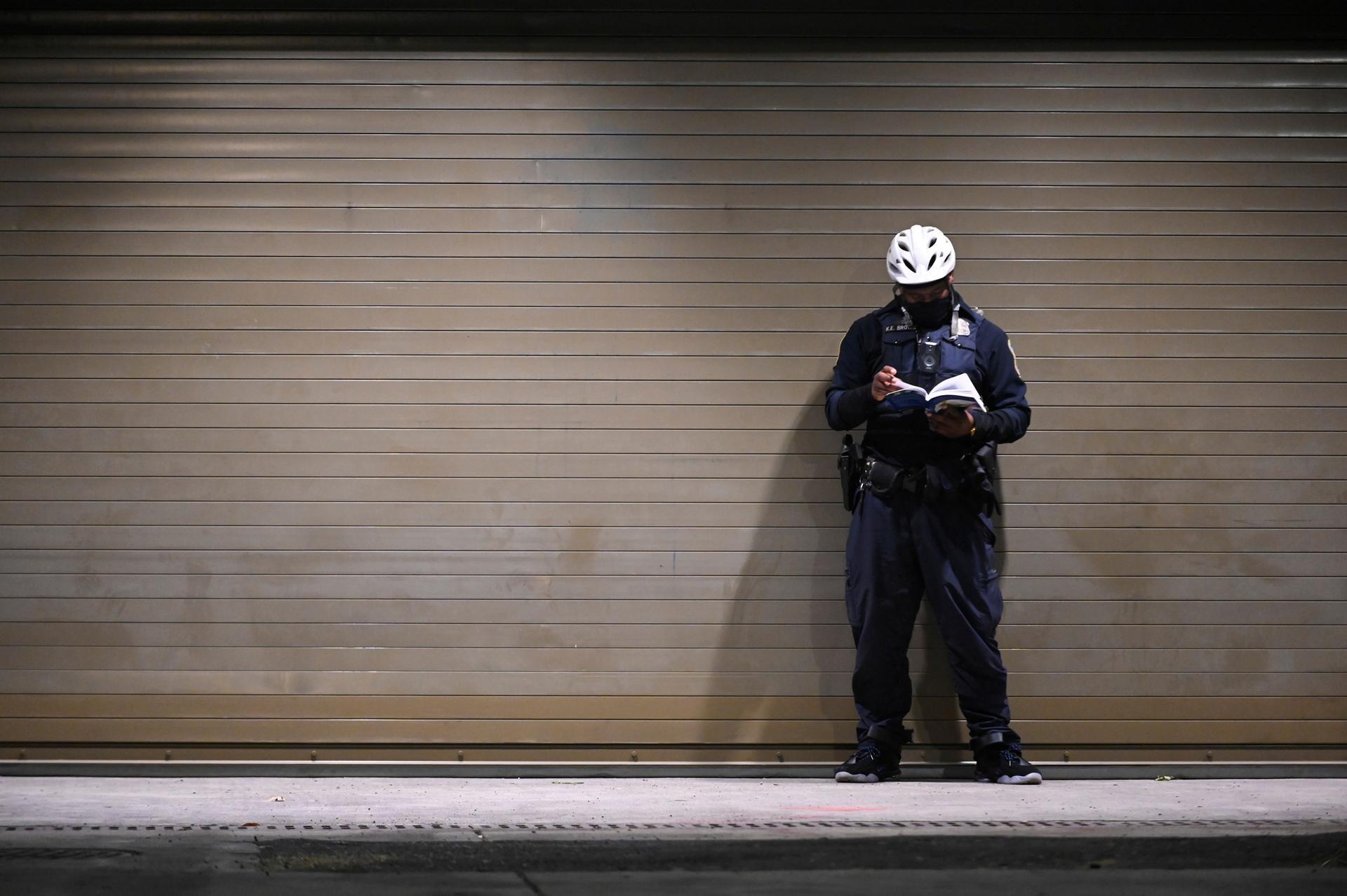 A police officer reads during a mostly uneventful night near the White House the day after the 2020 U.S. presidential election, in Washington. Reuters