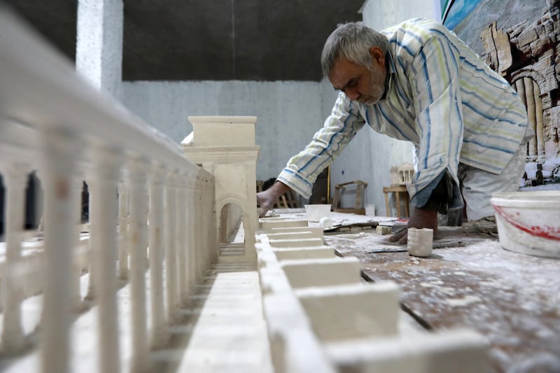 Ali Saleh, a 58-year-old displaced Syrian originally from Palmyra, builds from memory a wood and gypsum model of a prominent archaeological landmark of his home city that was heavily damaged by Islamic State (IS) militants, at a workshop home in the rebel-held city of al-Bab northwest of Aleppo in northern Syria on January 14, 2021. - Ten years of Syria's civil war have robbed Saleh of his home in the desert city, his three sons and daughter, and the last of his poor hearing, his family says. But he still vividly remembers Palmyra's ruins, where he accompanied restoration and excavation teams for 25 years, before the Islamic State group overran the city in 2015. (Photo by Bakr ALKASEM / AFP)