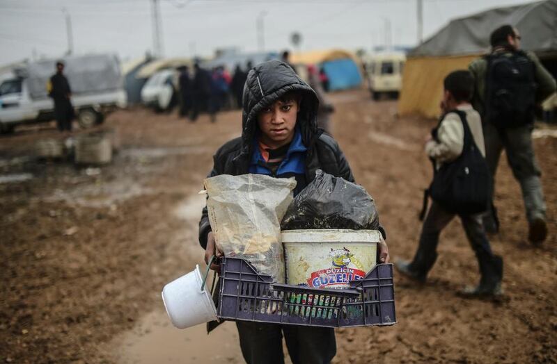 A child fleeing from Aleppo arrives with meagre belongings at the Turkish border crossing. (Bulent Kilic / AFP)