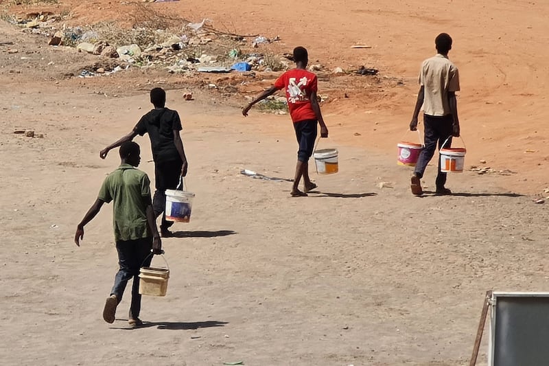 Youths carry buckets of water in the Sudanese capital. AFP