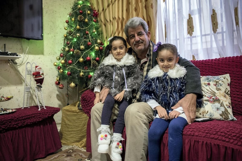 Louis Khno with his granddaughters Alina (left) and Angelina at his home in Qaraqosh, Iraq, 20 December 2017.