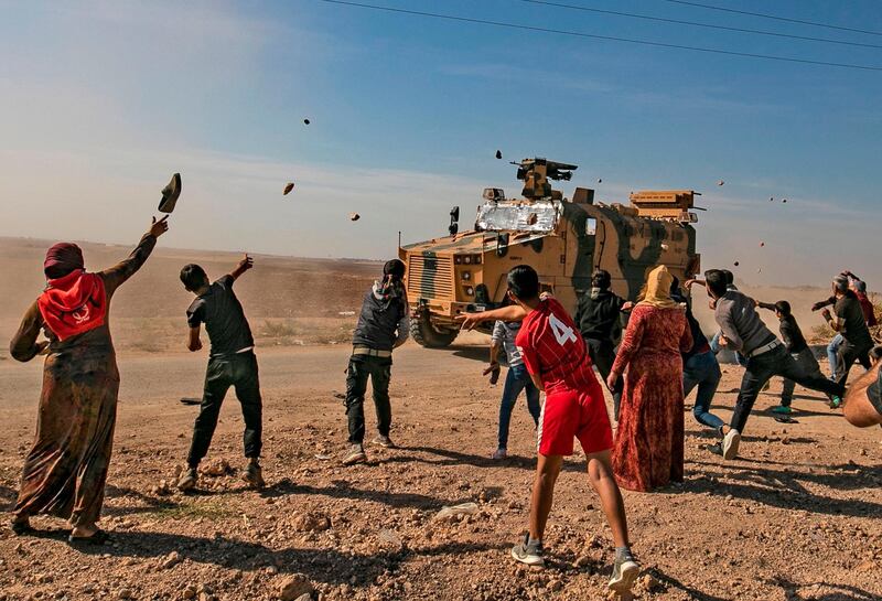 Syrians throw stones towards Turkish military vehicles during a Turkish-Russian army patrol near the town of Darbasiyah in Syria's northeastern Hasakeh province along the Syria-Turkey border. AFP