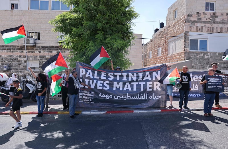 Palestinian and Israeli human rights campaigners lift banners during a rally near Augusta Victoria Hospital in East Jerusalem as US President Joe Binden visits. AFP