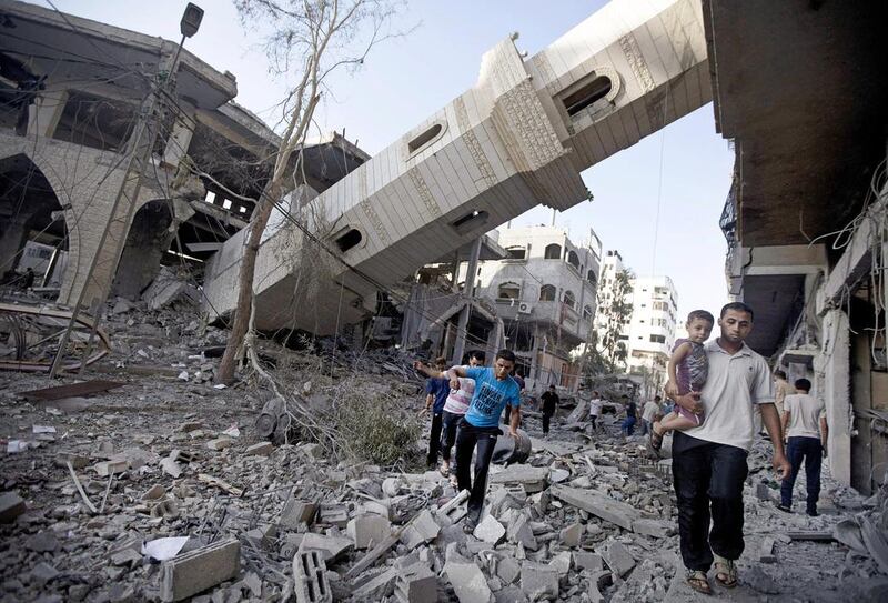 Palestinians walk past the collapsed minaret of a destroyed mosque in Gaza City on July 30 after it was hit in an overnight Israeli strike. AFP Photo


