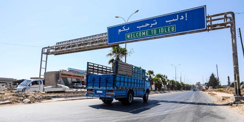 A truck drives past underneath a sign along the highway leading to the rebel-held northern Syrian city of Idlib on August 25, 2018. (Photo by OMAR HAJ KADOUR / AFP)