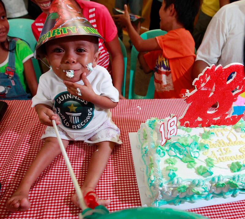 epa02776308 Junrey Balawing, smiles while eating a slice of his 18th birthday cake, after he was crowned as the shortest living man during a ceremony inside a municipal hall in Sindangan, Zamboanga del Norte, southern Philipipines on 12 June 2011. Junrey, a 23.59 inches or 59.93 centimeters tall , who struggles to walk and can not stand very long, replaced Nepalese Khagendra Megar, who stands 26.4 inches for distinction. 'We are very proud of him,' said his mother Concepcion.  EPA/DENNIS M. SABANGAN *** Local Caption ***  02776308.jpg