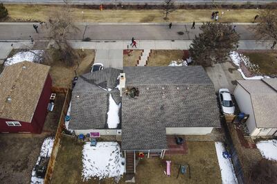 BROOMFIELD, CO - FEBRUARY 20: In this aerial view from a drone, people walk past a home with a hole in the roof from falling debris from an airplane engine on February 20, 2021 in Broomfield, Colorado. An engine on the Boeing 777 exploded after takeoff from Denver prompting the flight to return to Denver International Airport where it landed safely.   Michael Ciaglo/Getty Images/AFP
== FOR NEWSPAPERS, INTERNET, TELCOS & TELEVISION USE ONLY ==
