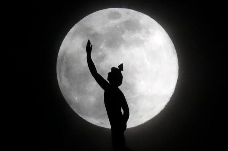A statue of the Roman god Mercury, mounted on a hotel in Nashville, US, is silhouetted by the supermoon. AP Photo