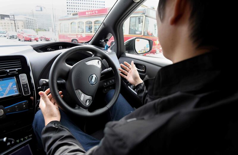This photo taken on February 21, 2018 shows a man sitting in the driver's seat of an auto driving Nissan electric vehicle named "Leaf" during a field test press preview in Yokohama, Kanagawa prefecture.
Nissan and information technology company DeNA announced on February 23 that they will begin a field test of Easy Ride, the robo-vehicle mobility service being developed by both companies, from March 5 until March 18. / AFP PHOTO / Toru YAMANAKA