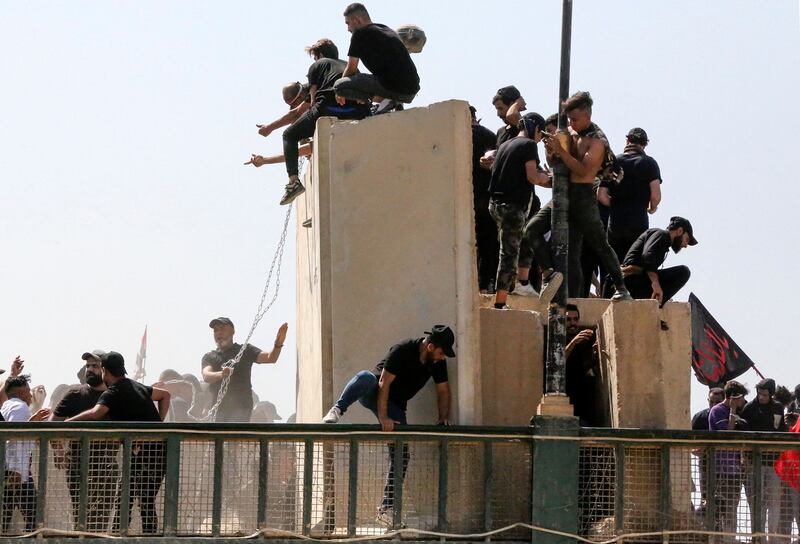 Supporters Moqtada Al Sadr use chains to try to bring down concrete barriers along the bridge. AFP
