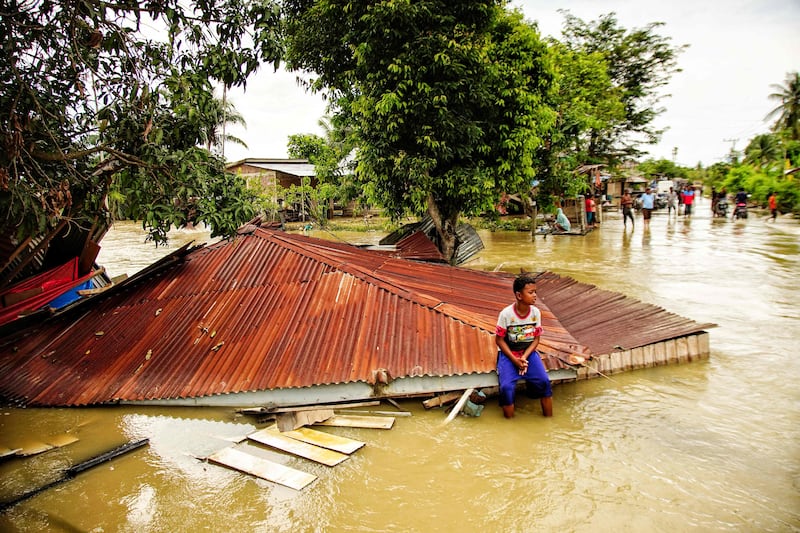 A villager sits on the roof of a flooded home in Lhokseumawe, in Indonesia's Aceh province, on October 10, 2022. AFP
