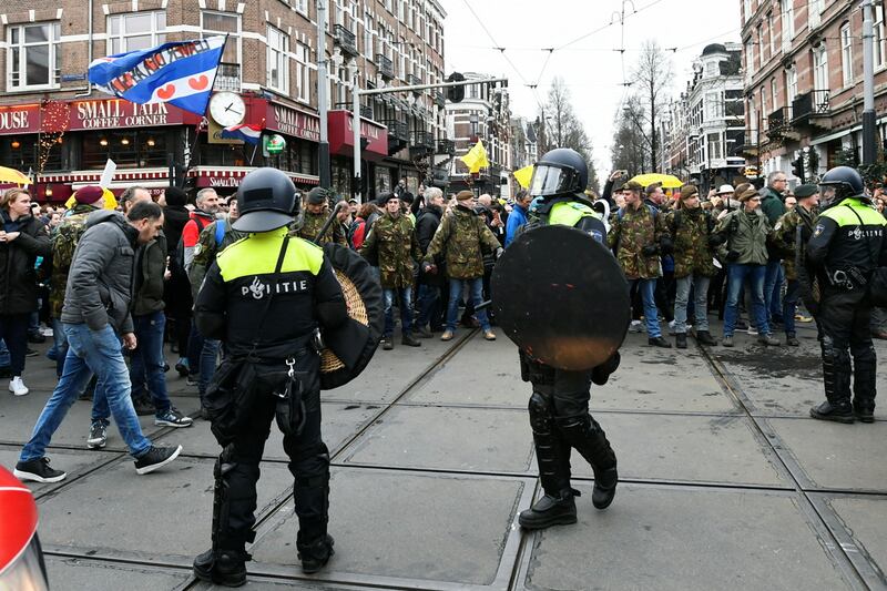 Police officers stand guard as opponents of restrictions imposed in the Netherlands to contain the spread of the coronavirus disease (Covid-19) protest despite a ban by local authorities, in Amsterdam, Netherlands, January 2, 2022. Reuters