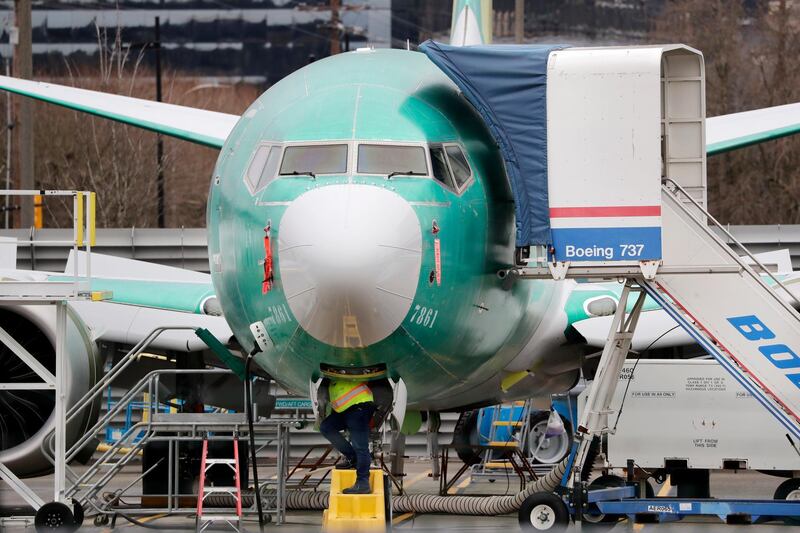 FILE - In this Dec. 16, 2019, file photo, a worker looks up underneath a Boeing 737 MAX jet, in Renton, Wash. Boeing has found a new software problem on its grounded 737 Max jetliner. The aircraft maker said, Friday, Jan. 17, 2020, it is making the necessary changes and working with the Federal Aviation Administration. (AP Photo/Elaine Thompson, File)