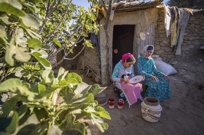 Moroccan potter Houda Oumal, left, paints with natural pigments on one of her pieces of pottery as her mother Fatima Harama looks on, near the village of Ourtzagh in the region of Taounate. AFP
