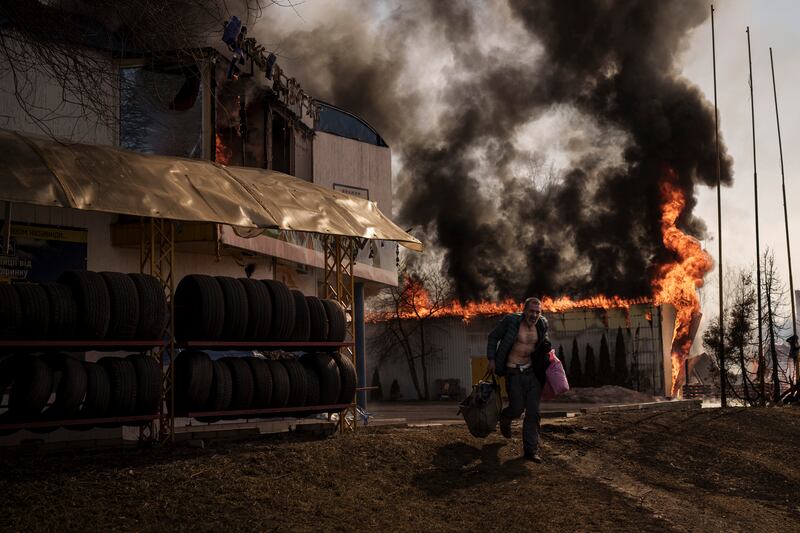 A man recovering items from a burning shop after a Russian attack in Kharkiv in March 2022