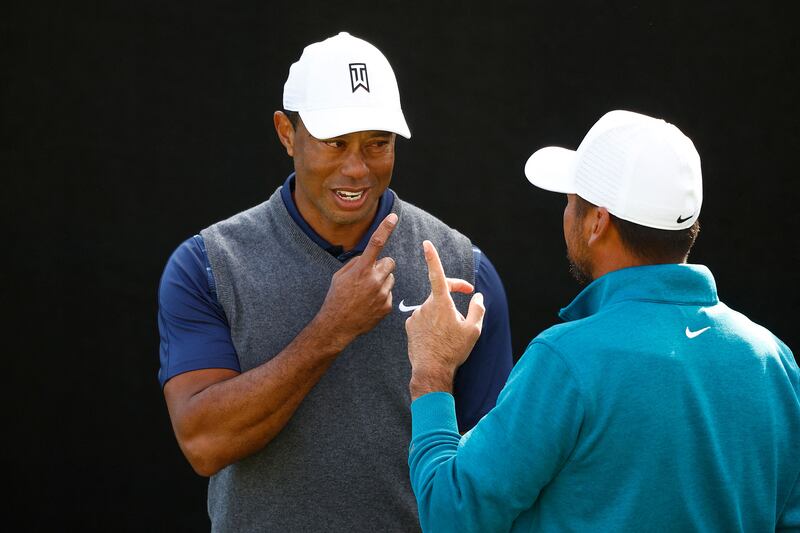 Tiger Woods and Jason Day talk while practicing on the putting green. Getty