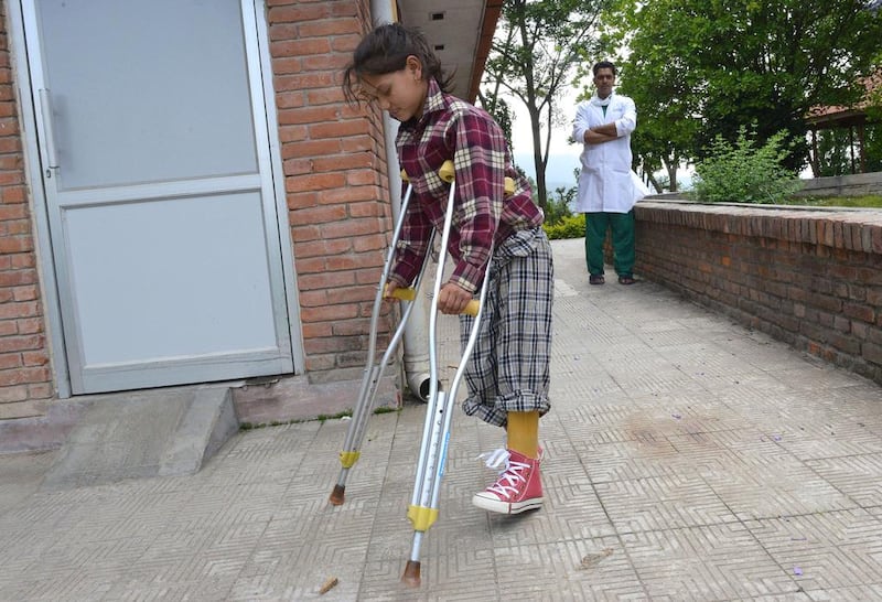 Nepalese child Maya Gurung is watched by a doctor as she walks with the aid of crutches in the grounds of a hospital in Banepal on the outskirts of Kathmandu. Maya is among thousands of Nepalese who face a daunting future after suffering loss of limbs, spinal and other permanent injuries in the twin quakes that claimed more than 8,700 lives. AFP PHOTO/Prakash MATHEMA

