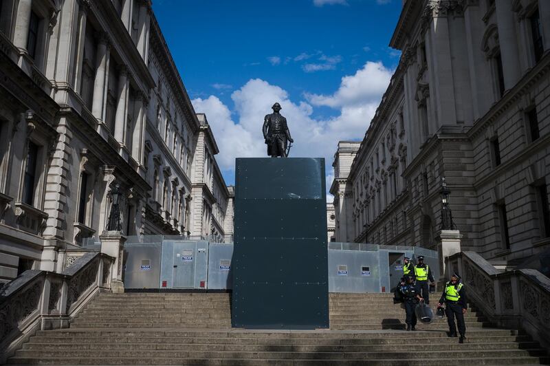 LONDON, UNITED KINGDOM - JUNE 21: Police officers in riot clothing pass by a protected statue of Robert Clive, also known as "Clive of India", as they return to their vehicles after a Black Lives Matter rally in Parliament Square on June 21, 2020 in London, United Kingdom. Robert Clive is credited with establishing British rule in India for the East India Company through military campaigns against the French and Indian native rulers. Black Lives Matter protests are continuing across the UK following the death of African American George Floyd at the hands of police officers in Minneapolis on May 25, 2020. The movement has triggered the removal of statues with links to racism and the slave trade and has gained support from many high-profile celebrities and sports stars. (Photo by Leon Neal/Getty Images)