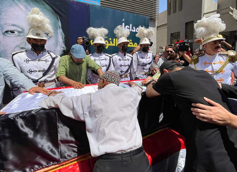 Mourners cry over the casket. AFP
