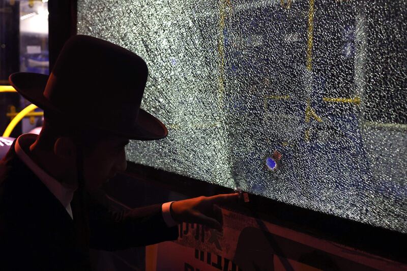 A security forces member examines what appears to be a bullet hole in a shattered window. AFP