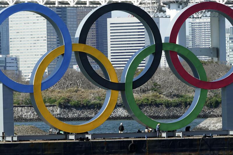 Workers stand at the bottom of the Olympic rings at Tokyo's Odaiba district. AP
