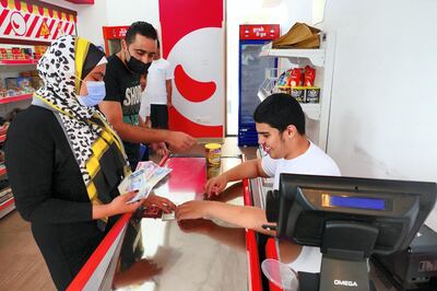 Omar Al Suwaidan (right) as a cashier at the Zoom market at the Sanad village mall in Dubai Sustainable City on April 29,2021. This centre is for people of determination fit out with real simulation zones like malls, clinics and an airport to help students gain independence. Pawan Singh / The National. Story by Kelly