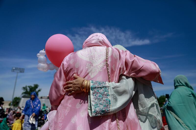 Two women embrace after performing Eid Al Fitr prayers on the Niles West High School football field in Skokie, Illinois.