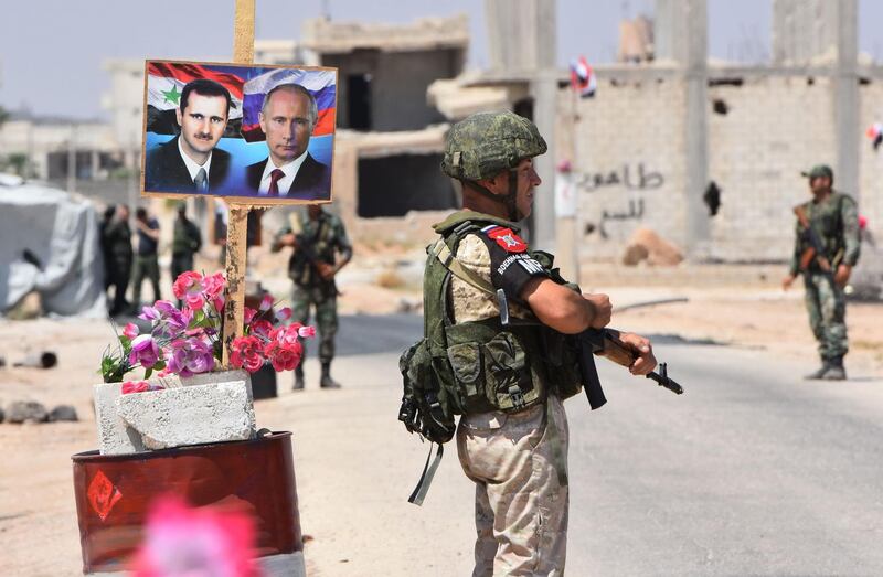 (FILES) In this file photograph taken on August 20, 2018, members of Russian and Syrian forces stand guard near posters of Syrian President Bashar al-Assad and his Russian counterpart Vladimir Putin at the Abu Duhur crossing on the eastern edge of Idlib province. - Russia and Turkey are in intense negotiations to ensure the rebel-held province of Idlib does not become a breaking point in their alliance on Syria, but the long term fate of the area still risks provoking a rupture, analysts say. President Vladimir Putin and Turkish counterpart Recep Tayyip Erdogan have spearheaded an unlikely but so far sustained partnership to bring peace to Syria since late 2016, despite being in theory on opposite sides of the civil war.The cooperation now faces its biggest test over Syria's northwestern province of Idlib, bordering Turkey, which Syrian President Bashar al-Assad wants to recapture to complete a string of military successes. (Photo by George OURFALIAN / AFP)