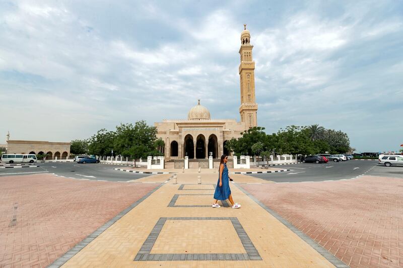 Dubai, United Arab Emirates - May 19, 2019: A tourist walks passed a mosque on a cloudy hazy day in Dubai. Sunday the 19th of May 2019. Jumeirah, Dubai. Chris Whiteoak / The National