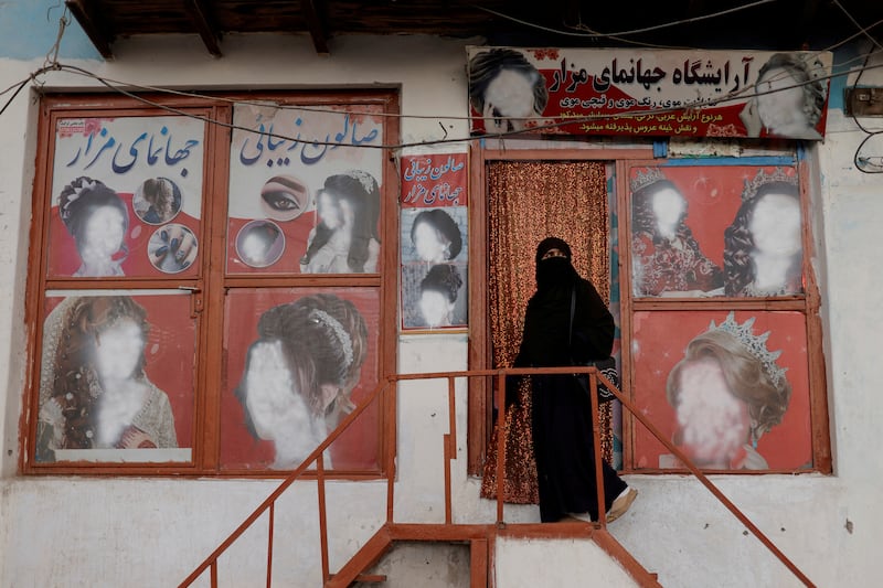 An Afghan woman enters a beauty salon where the adverts have been defaced, in Kabul. Reuters