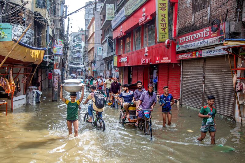 A Bangladeshi rickshaw puller rides through a flooded street in Dhaka. EPA