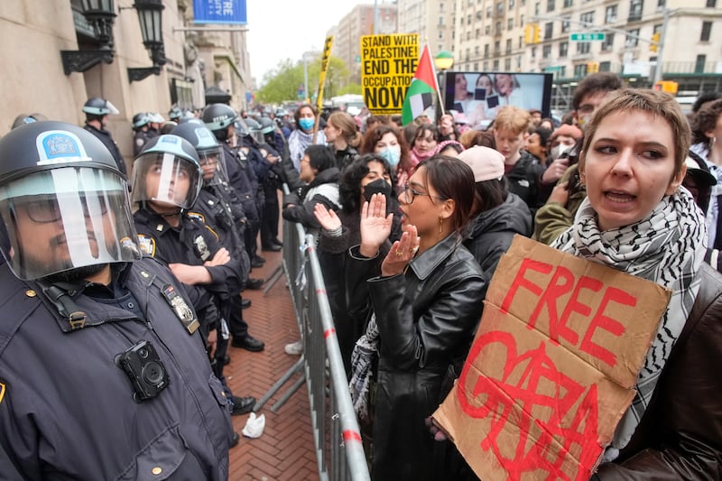 Police in Riot gear stand guard as demonstrators chant slogans outside the Columbia University campus. AP