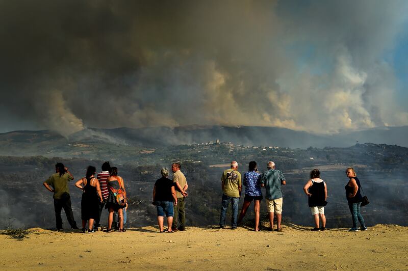 Local people watch clouds of smoke during a forest fire in Linhares da Beira, northern Portugal. EPA