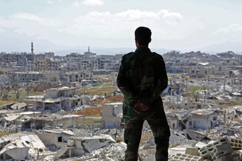 A Syrian soldier looks at destroyed buildings nearly a week after retaking the town of Harasta from the rebels, in Eastern Ghouta on the outskirts of the capital Damascus, on March 29, 2018.
An agreement between Russia and the Islamist faction Faylaq al-Rahman has already seen nearly 20,000 people quit the towns of Arbin and Zamalka and the Jobar district since last week. / AFP PHOTO / STR