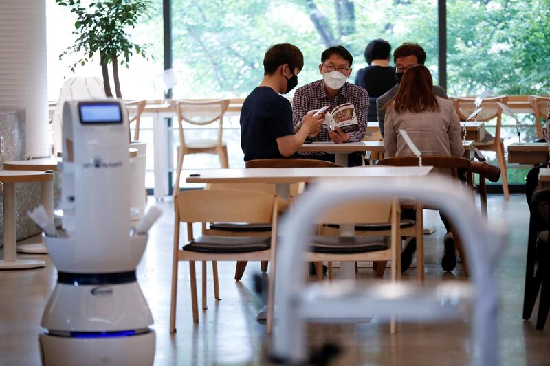 Customers wait at a cafe where a robot that takes orders, makes coffee and brings the drinks straight to customers is being used in Daejeon, South Korea, May 25, 2020. REUTERS/Kim Hong-Ji