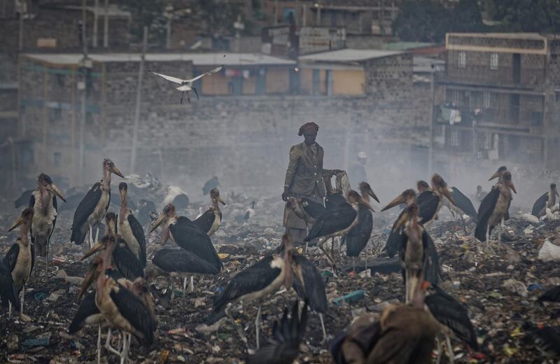 A woman who scavenges recyclable materials from garbage for a living is seen through a cloud of smoke created by burning trash at the dump in the Dandora slum of Nairobi, Kenya. AP Photo