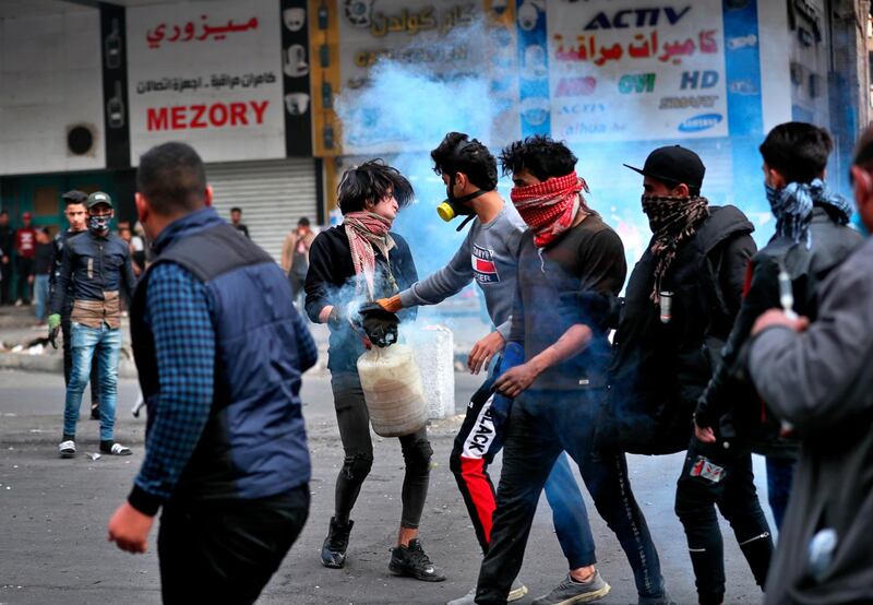 Protesters extinguish a tear gas canister in water during clashes with Iraqi security forces in Baghdad. AP Photo