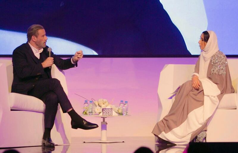 In this Friday, Dec. 15, 2017 photo released by Saudi Arabia Center for International Communication, Ministry of Culture and Information, John Travolta, left, talks at the Apex Convention Center in Riyadh, Saudi Arabia. (Center for International Communication, Ministry of Culture and Information via AP)